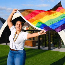 Load image into Gallery viewer, woman with rainbow flag black and brown stripes qtipoc poc flag