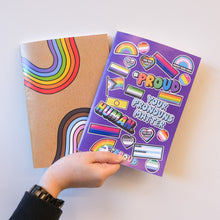 Load image into Gallery viewer, Hand holding a purple sticker notebook, alongside a notebook with rainbow designs.