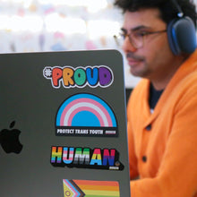 Load image into Gallery viewer, lgbtqia inclusion stickers on a laptop, with a person out of focus in the background